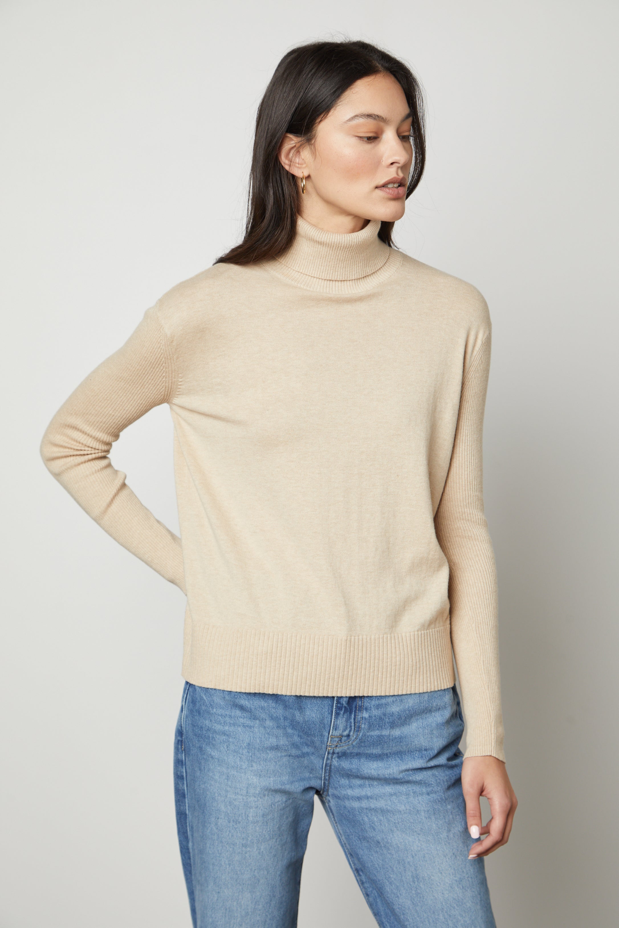 A model wearing the Velvet by Graham & Spencer Sally Mock Neck Sweater and jeans.