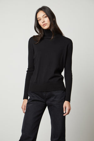 A woman wearing a Velvet by Graham & Spencer Sally Mock Neck Sweater and black jeans.