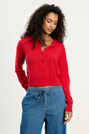 A woman wears the VIOLETTE CARDIGAN by Velvet by Graham & Spencer, paired with blue drawstring denim pants, standing against a plain light background.