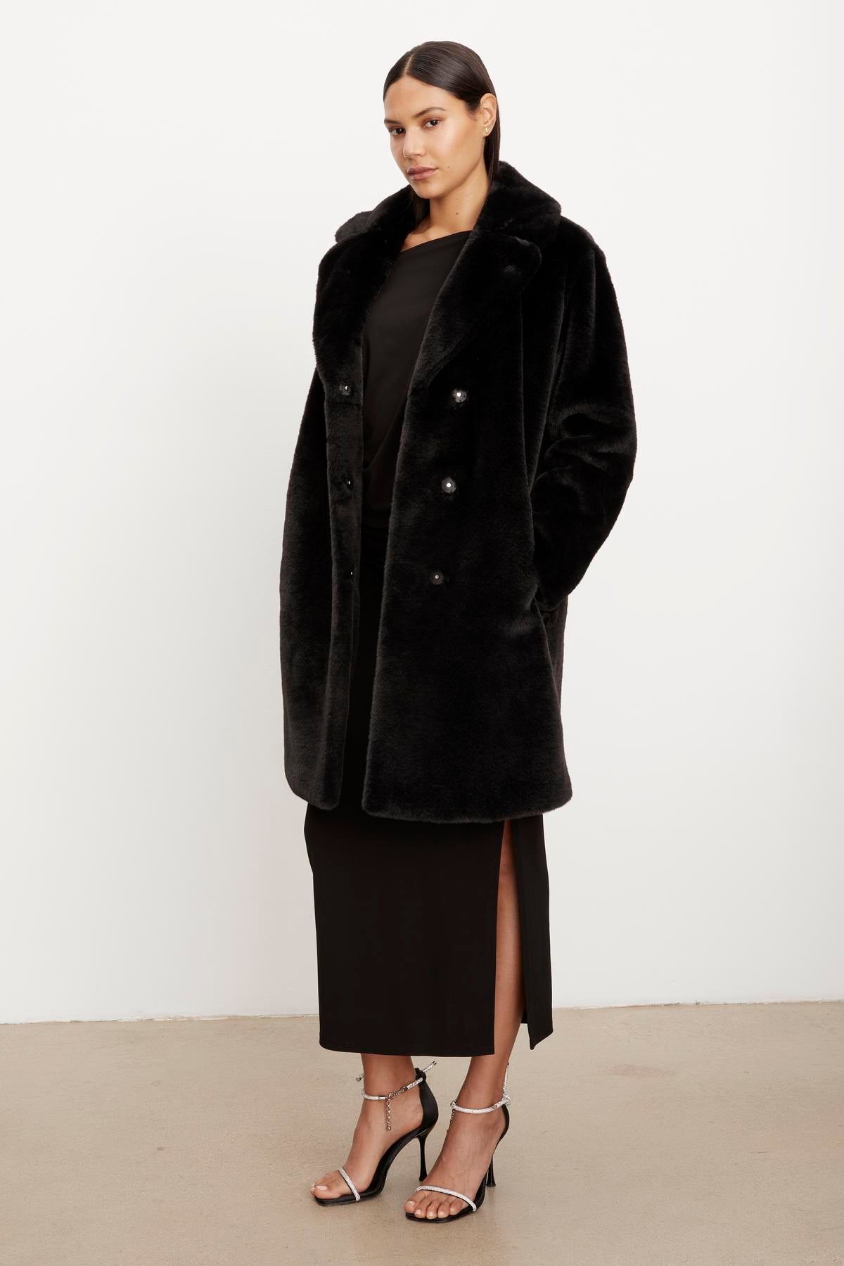 The model is wearing a Velvet by Graham & Spencer EVALYN LUX FAUX FUR COAT.