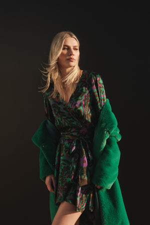 A woman in a green dress and Velvet by Graham & Spencer EVALYN LUX FAUX FUR COAT.