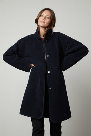 A woman wearing a Velvet by Graham & Spencer CARA LUX SHERPA REVERSIBLE JACKET and black pants.