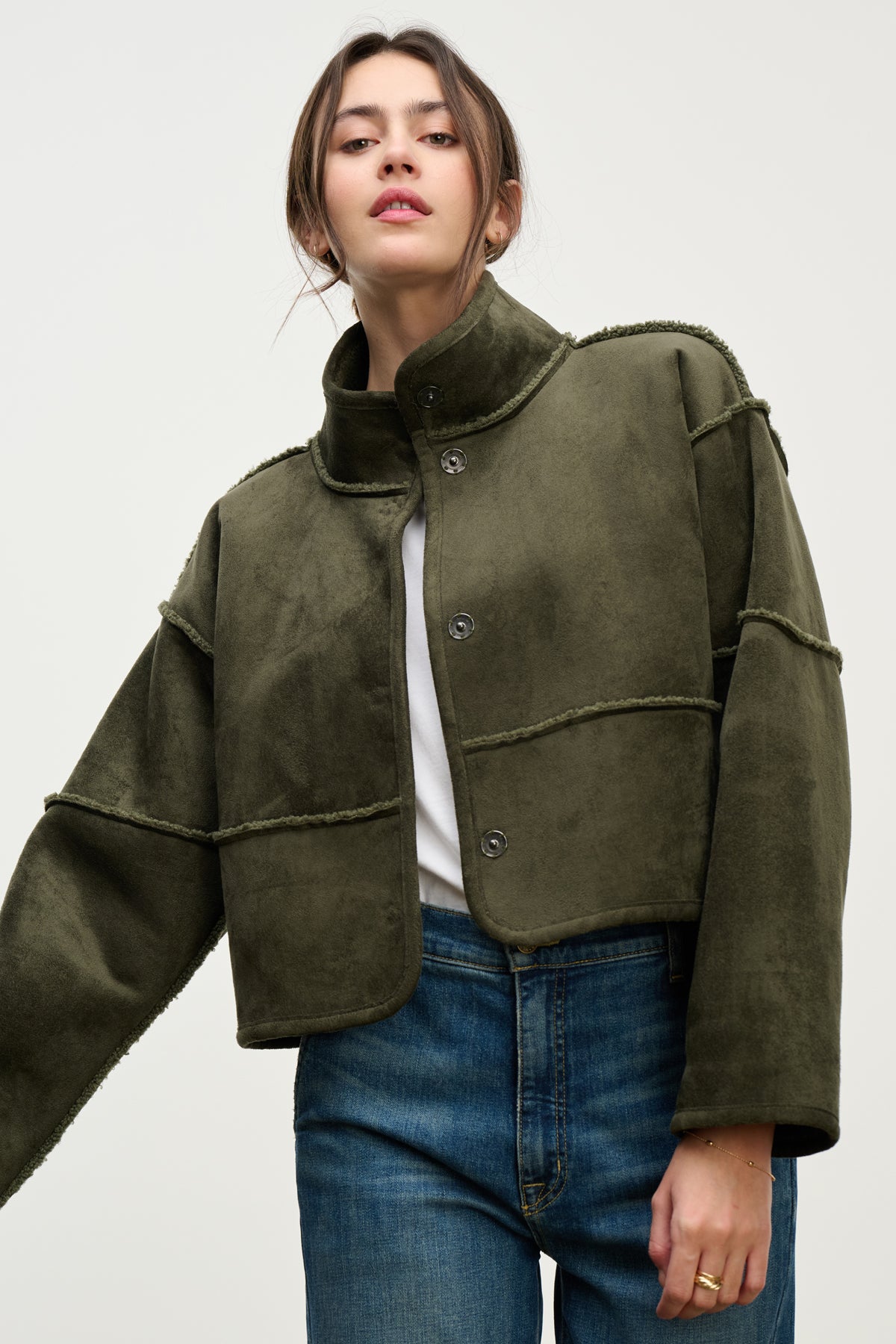 A woman wears the Velvet by Graham & Spencer KELLY LUXE SHERPA REVERSIBLE JACKET, styled over a white top and blue jeans, standing against a plain light background.