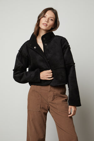 The model is wearing a Velvet by Graham & Spencer KELLY LUX SHERPA REVERSIBLE JACKET and brown pants.