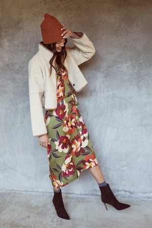 A woman wearing a floral dress and a beanie with the Velvet by Graham & Spencer KELLY LUX SHERPA REVERSIBLE JACKET.