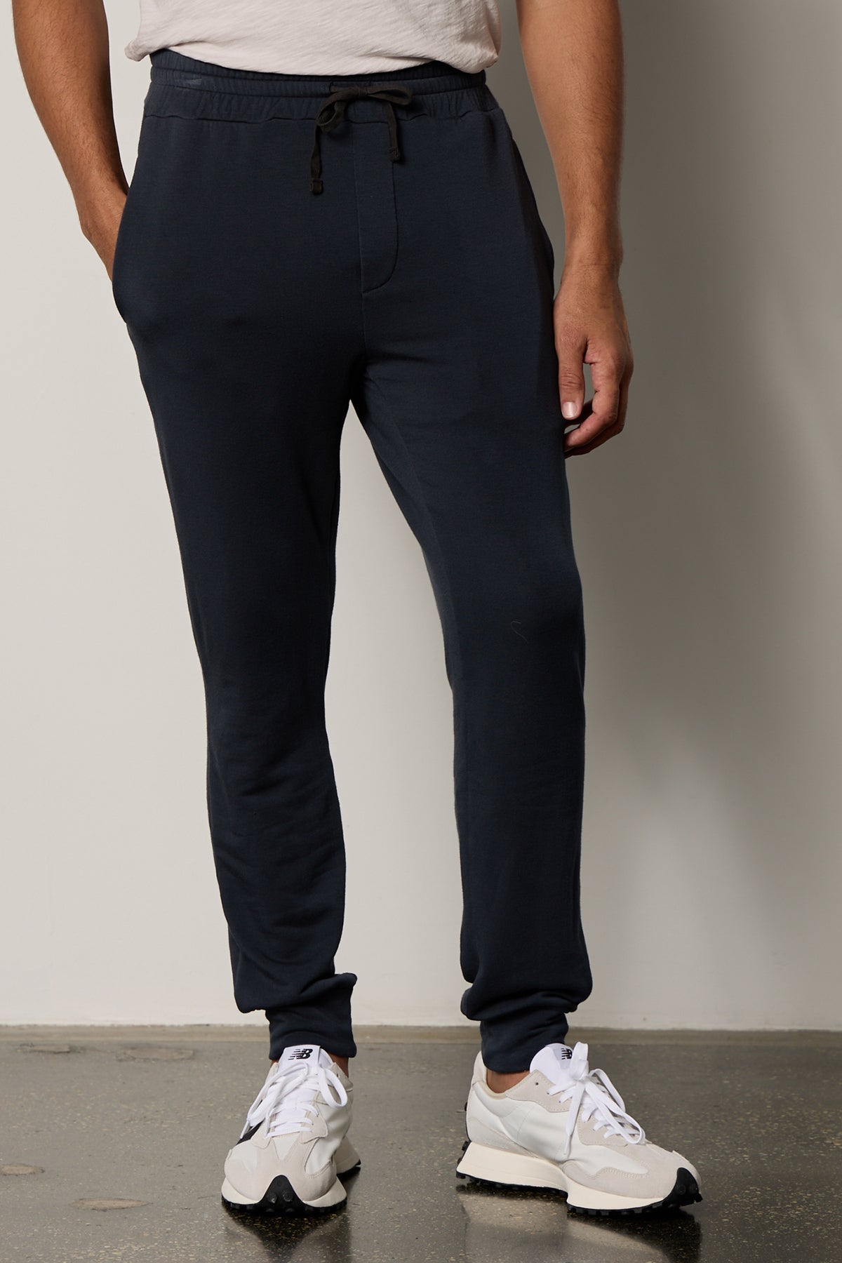 A man wearing the Velvet by Graham & Spencer CROSBY LUXE FLEECE JOGGER and white sneakers.