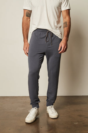 A man wearing Crosby Luxe Fleece Jogger sweatpants by Velvet by Graham & Spencer and a white t-shirt for workouts.