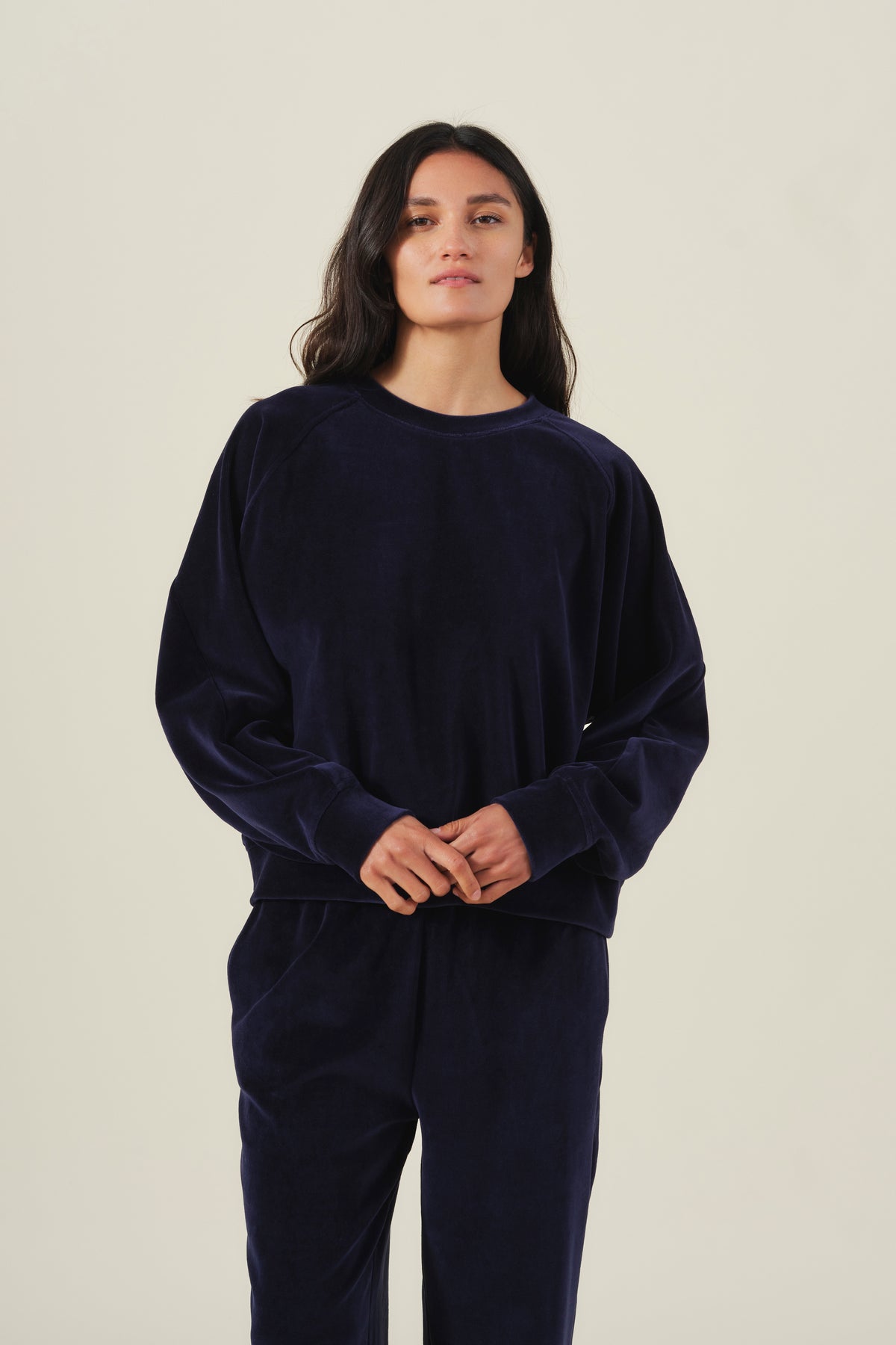 A person wearing a dark blue CALLIE VELOUR SWEATSHIRT and matching pants.-46489864962241