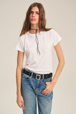 A woman wears the MARIE TEE by Velvet by Graham & Spencer—a casual cotton slub, boxy-fit top—styled with blue jeans, a black belt, and a slim black necklace against a neutral background.