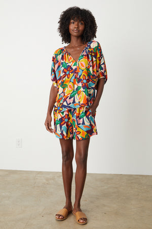 A woman wearing a ROBIN PRINTED LINEN TOP by Velvet by Graham & Spencer and sandals.