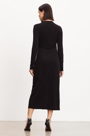 The back view of a woman wearing the Velvet by Graham & Spencer ELIANA WRAP MIDI DRESS.