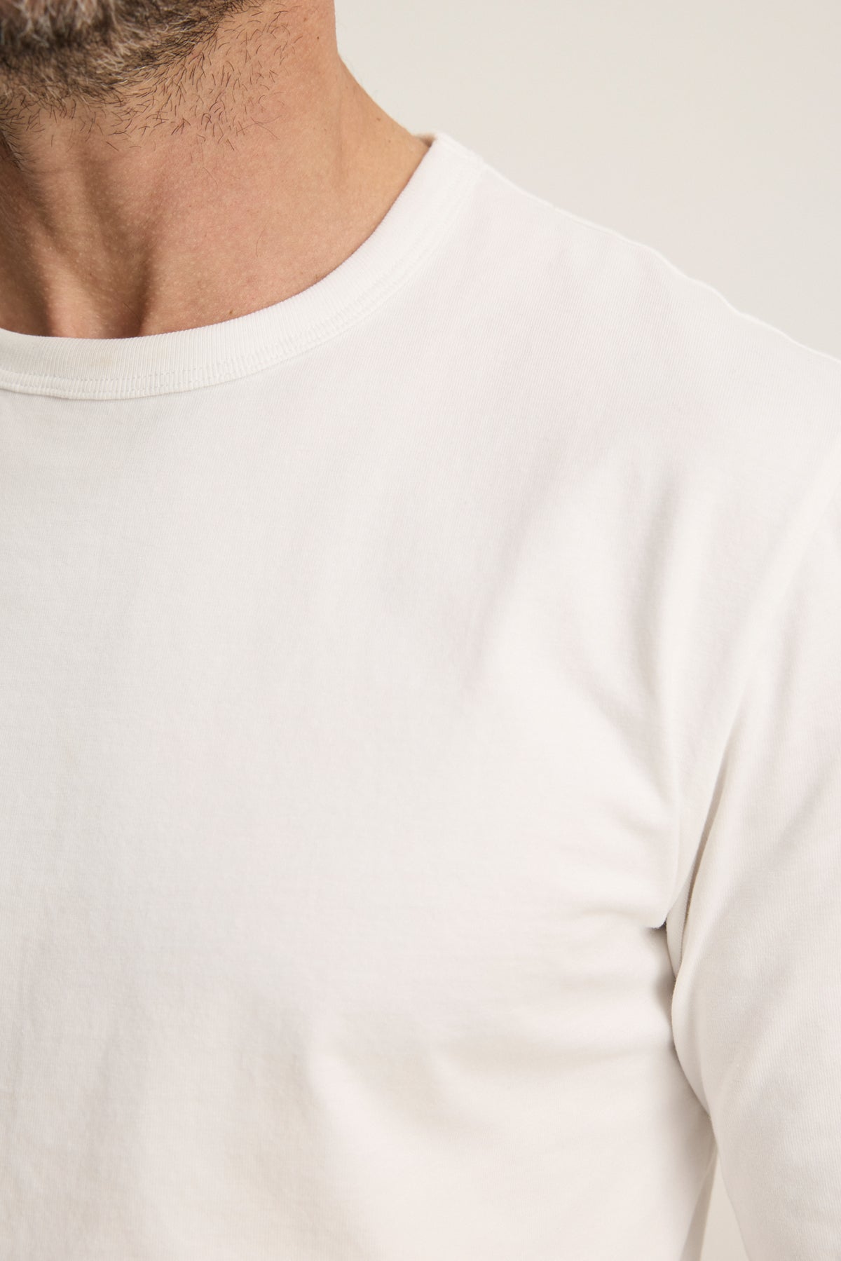 Close-up of a person wearing the ANTONIO TEE by Velvet by Graham & Spencer, a relaxed fit white cotton jersey crew-neck t-shirt, highlighting the neck, shoulder, and upper chest.