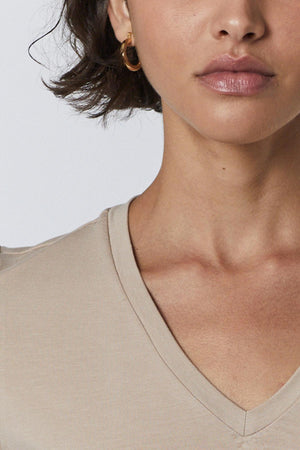 A woman wearing a classic tan Runyon Tee by Velvet by Jenny Graham, perfect as a base layer under a suit jacket.