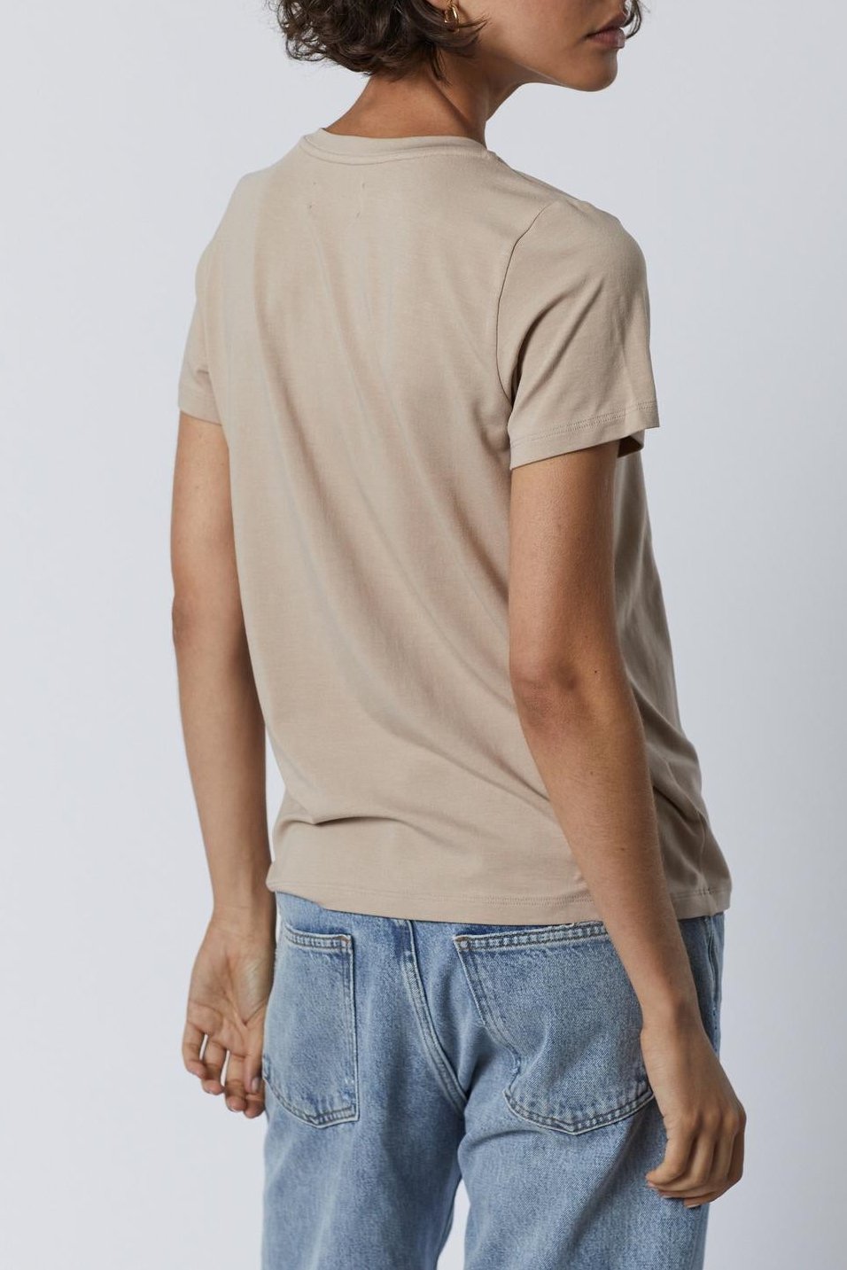 The back view of a woman wearing a Velvet by Jenny Graham RUNYON TEE and jeans as her base layer.-35416706646209