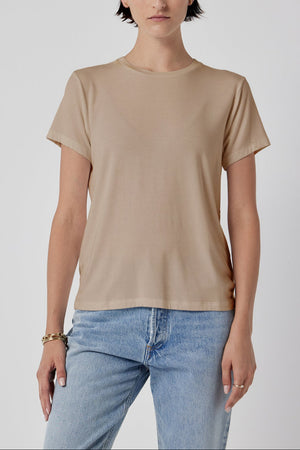 Woman modeling a classic Solana Tee by Velvet by Jenny Graham in beige and blue jeans against a white background.