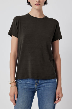 A woman in a Solana Tee by Velvet by Jenny Graham and blue jeans standing against a white background.