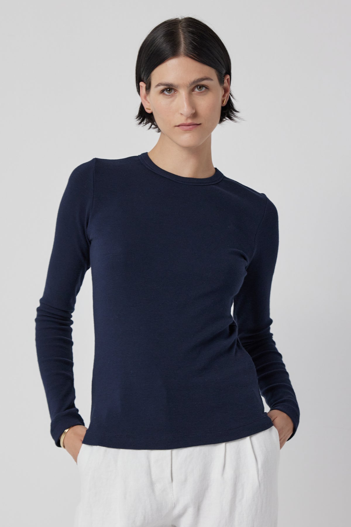  Woman wearing a slimmer fit navy blue long-sleeve CAMINO TEE by Velvet by Jenny Graham and white pants. 