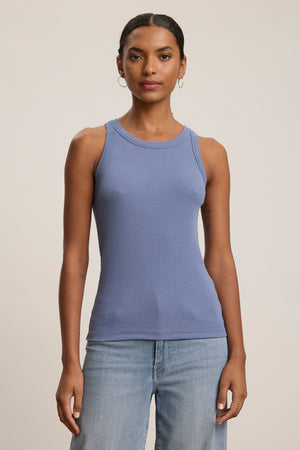 A woman faces forward in the CRUZ TANK TOP by Velvet by Jenny Graham—a versatile ribbed cotton-modal blue tank styled with light blue jeans, against a neutral background. Perfect for any capsule wardrobe.