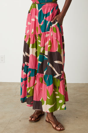 A woman wearing a pink, green, and blue printed tiered skirt.
