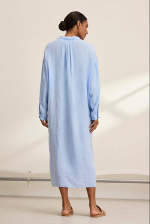 With their back to the camera, a person wears the breathable and versatile NICOLE LINEN DRESS in light blue, designed by Velvet by Graham & Spencer.