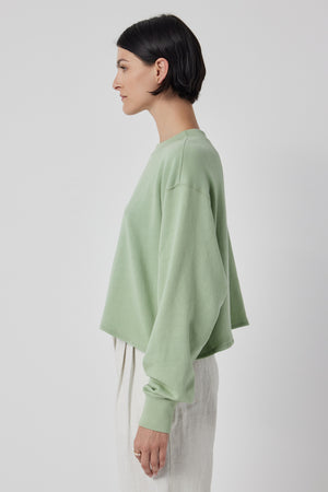 The back view of a woman wearing a Velvet by Jenny Graham MALIBU SWEATSHIRT with a cropped silhouette and white pants.