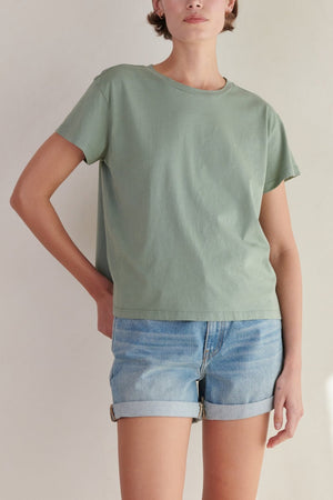 the model is wearing a Velvet by Jenny Graham sage green TOPANGA Tee and denim shorts.