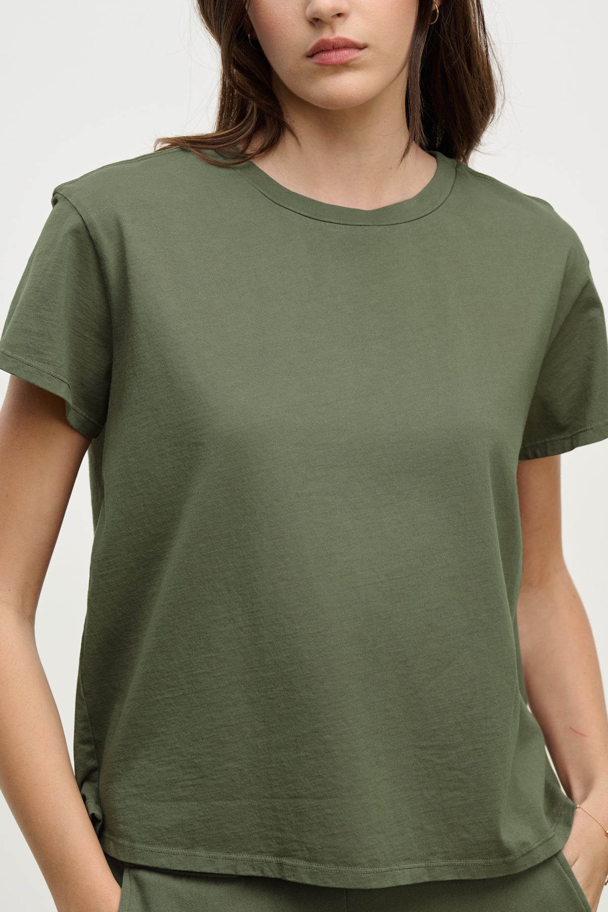 A person is wearing the TOPANGA TEE by Velvet by Jenny Graham, a relaxed-fit olive green t-shirt crafted from organic cotton, hands in pockets against a plain background.-38928282779841