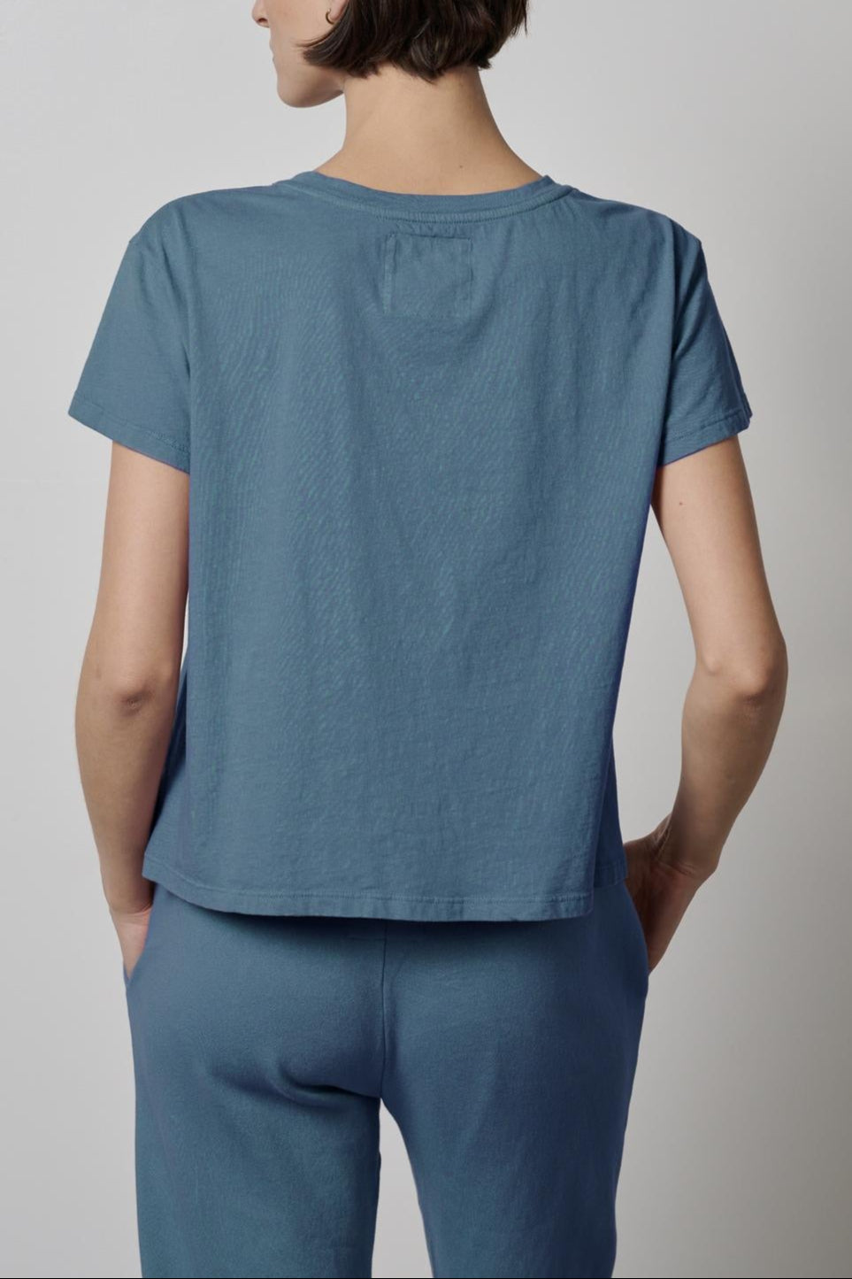 The back view of a woman wearing a blue Velvet by Jenny Graham TOPANGA TEE and pants.-35721216884929