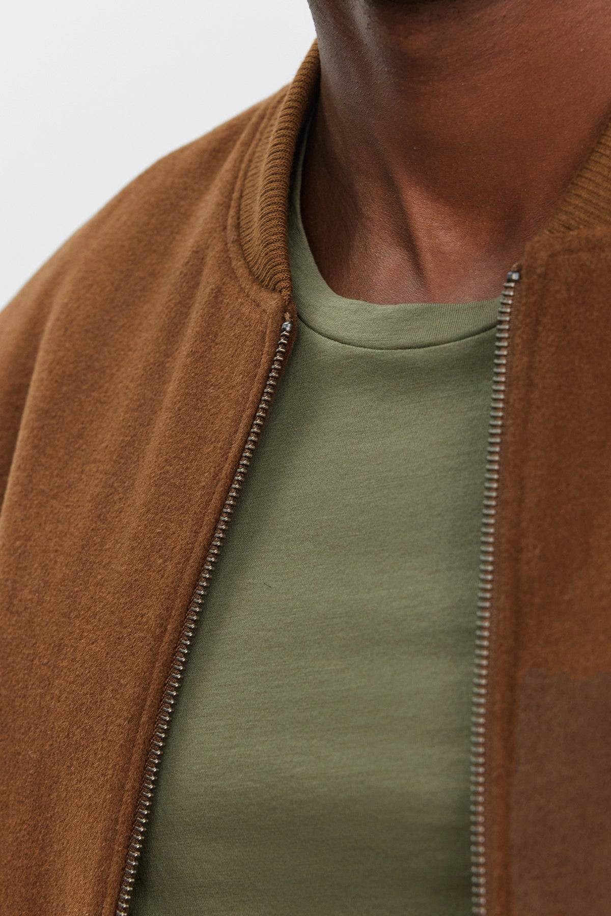 Close-up of a person wearing the FRAZIER BOMBER JACKET by Velvet by Graham & Spencer over an olive green t-shirt, showing only the neck and upper chest.-39316905820353