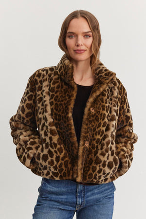A woman wearing the VALLI FAUX FUR JACKET by Velvet by Graham & Spencer and blue jeans stands against a plain background.