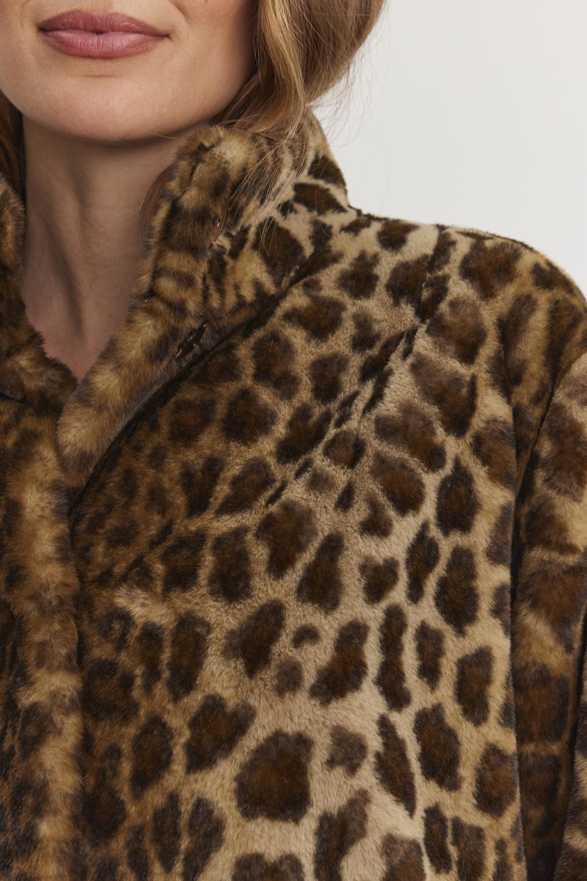 Close-up of a person wearing the VALLI FAUX FUR JACKET by Velvet by Graham & Spencer, highlighting the fabric texture and leopard-print pattern.