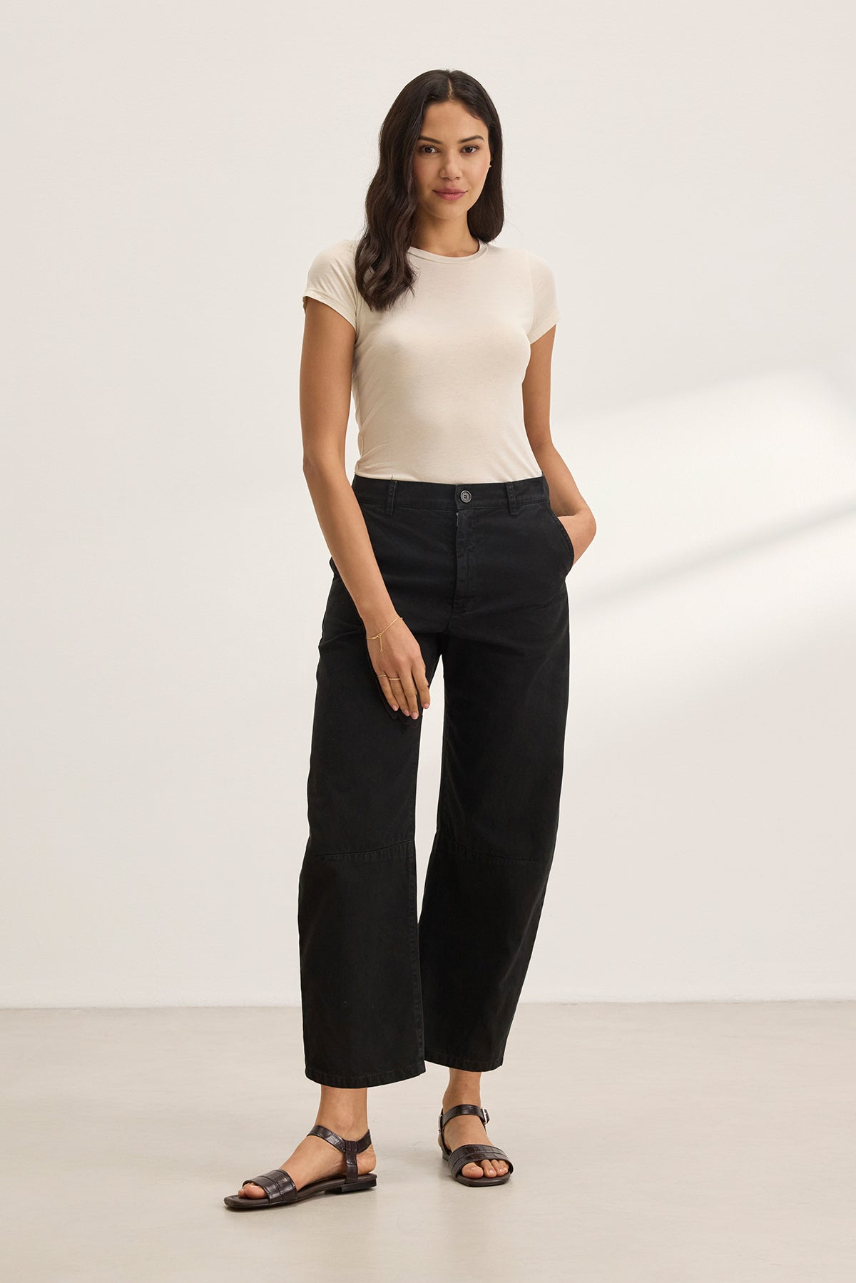 Someone in a light t-shirt and Velvet by Graham & Spencer's ALEXIS PANT, cropped at the ankle, stands against a plain background with hands in pockets.-38662632014017