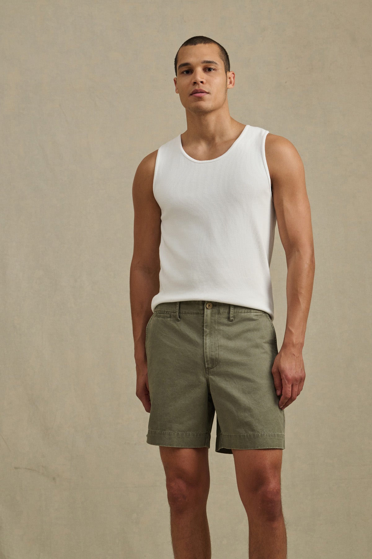 A man stands against a plain background wearing a white tank top and Velvet by Graham & Spencer JOEL SHORT in olive green cotton twill, facing forward with a neutral expression.-41338470138049