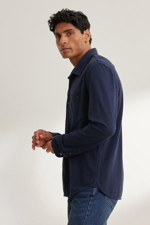 A person wearing a GIORGIO PIQUE BUTTON-UP SHIRT by Velvet by Graham & Spencer and jeans, looking towards the camera against a plain background.