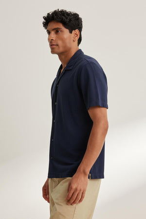 A person wearing the Velvet by Graham & Spencer MARTYN PIQUE BUTTON-UP SHIRT in navy blue and beige pants stands against a neutral background.