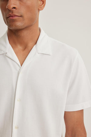 Man wearing a MARTYN PIQUE BUTTON-UP SHIRT by Velvet by Graham & Spencer, featuring a white short-sleeve design against a plain background.