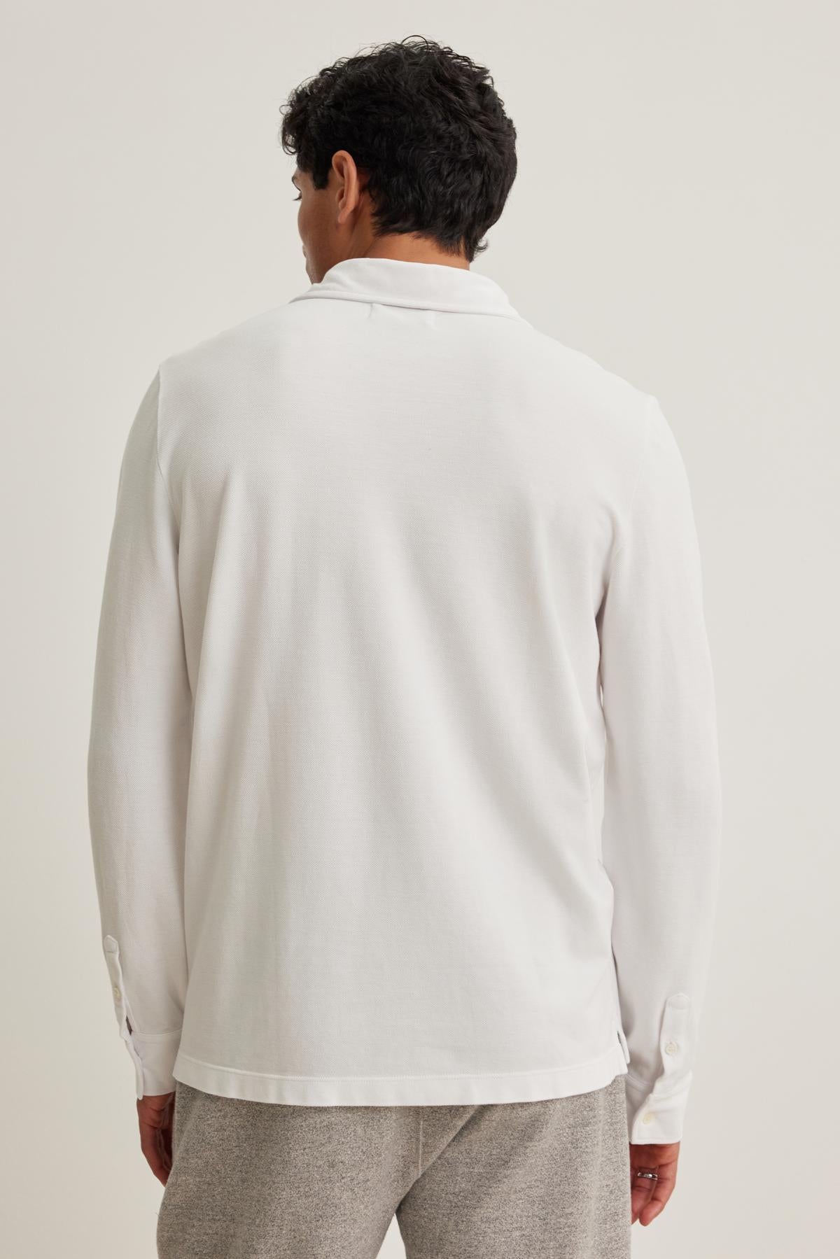 Person wearing the SACHA PIQUE POLO by Velvet by Graham & Spencer and gray pants, standing with their back to the camera against a plain background.