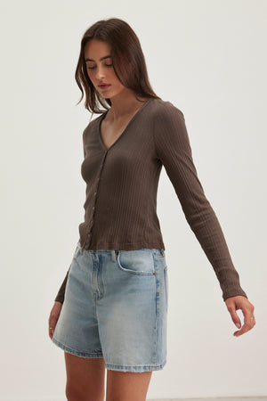 A person in a Velvet by Graham & Spencer DREW POINTELLE CARDIGAN and light blue denim shorts stands against a plain background.