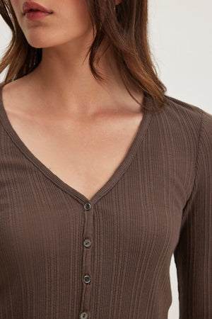 A woman in the brown DREW POINTELLE CARDIGAN by Velvet by Graham & Spencer is shown from shoulders to waist, facing slightly left. Made from a comfortable cotton-modal blend with a V-neckline, this ribbed button-up top is perfect for layering and offers elegance and versatility.