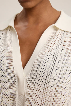 Close-up of a person wearing the MILA POINTELLE LACE DRESS by Velvet by Graham & Spencer, featuring white cotton fabric, a collared deep V-neck, and textured vertical openwork—ideal as a lightweight beach cover-up.
