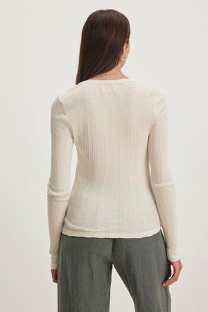The back view shows someone wearing Velvet by Graham & Spencer's MAURI POINTELLE TEE, a white ribbed long-sleeve made from a soft cotton-modal blend, paired with gray pants against a plain background.