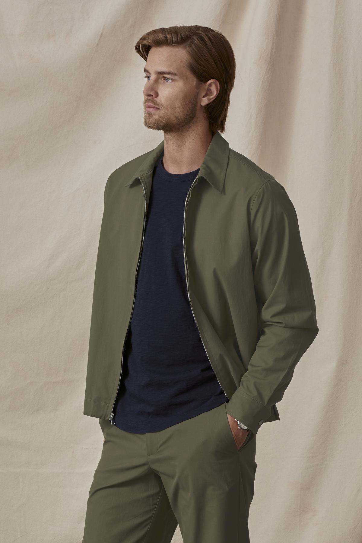 Man in Velvet by Graham & Spencer ALTON POPLIN ZIP-UP JACKET with snap buttons and trousers with navy blue shirt, posing against a beige backdrop.-36299656265921