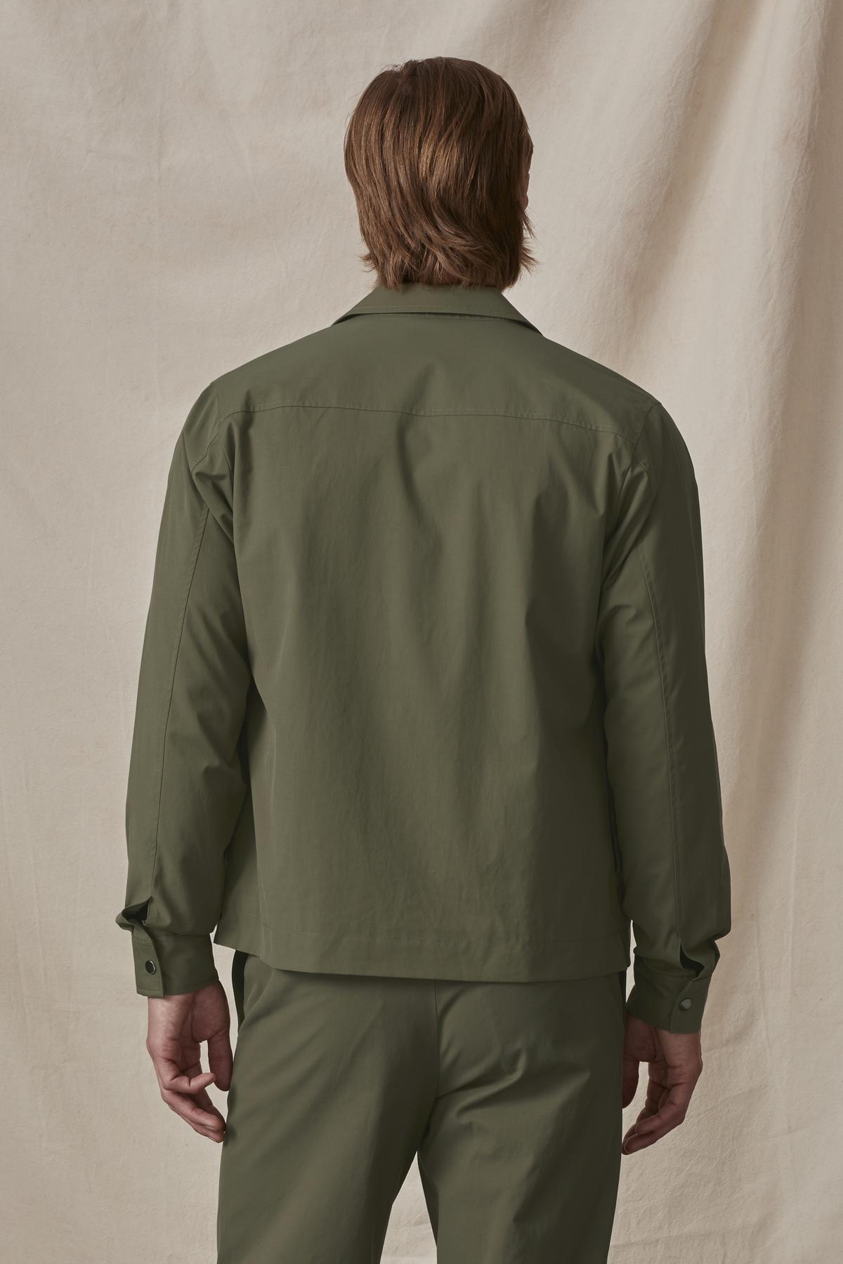   Man wearing a green velvet by Graham & Spencer cotton blend shirt and pants, viewed from behind. 