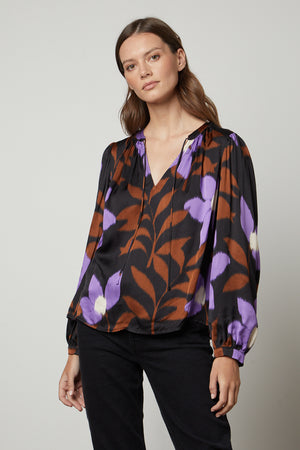 A woman wearing an ISRA printed V-neck blouse by Velvet by Graham & Spencer.