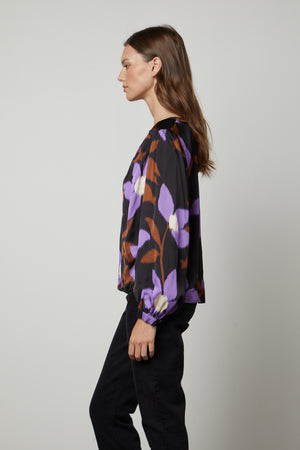 A woman wearing the Velvet by Graham & Spencer ISRA PRINTED V-NECK BLOUSE in purple and black.