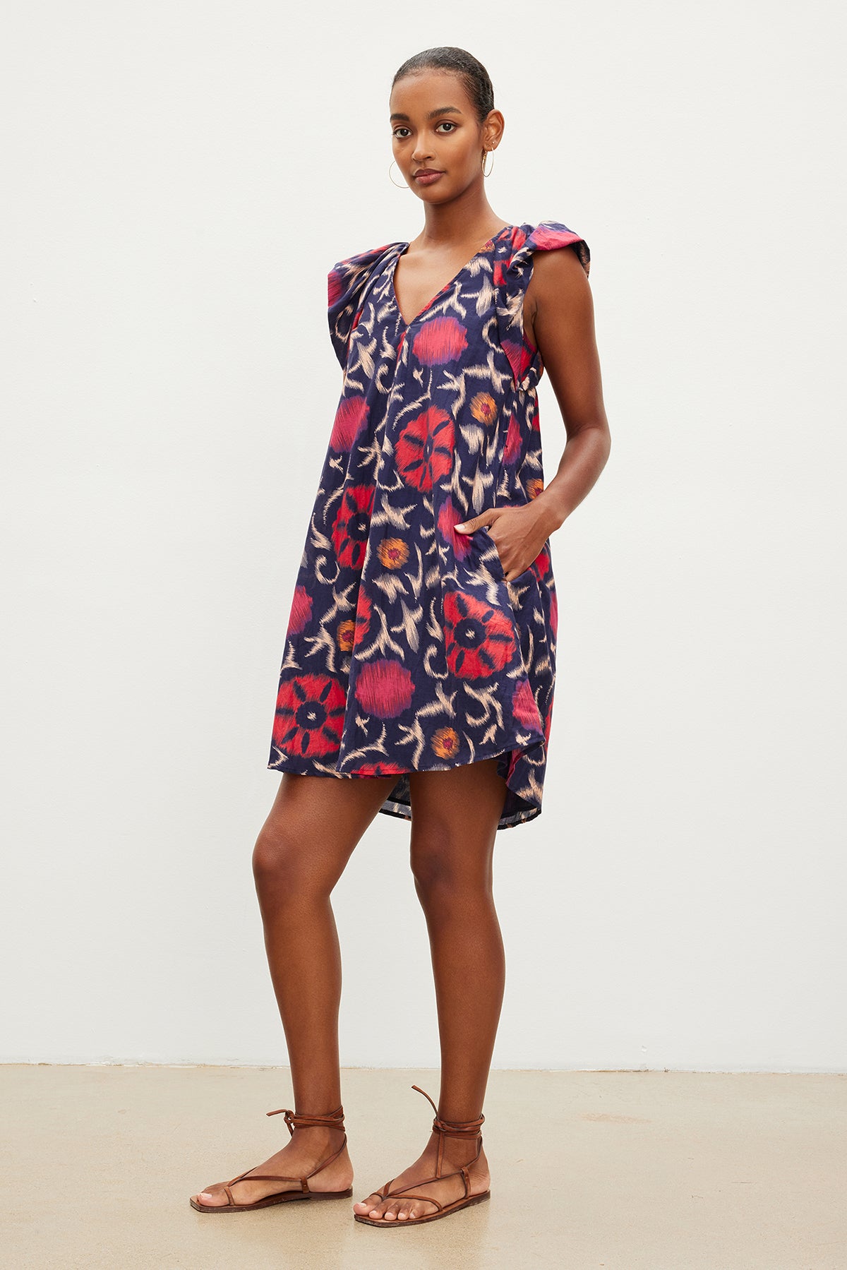 The model is wearing a Velvet by Graham & Spencer JENNA PRINTED SILK COTTON VOILE DRESS with ruffles and sandals.