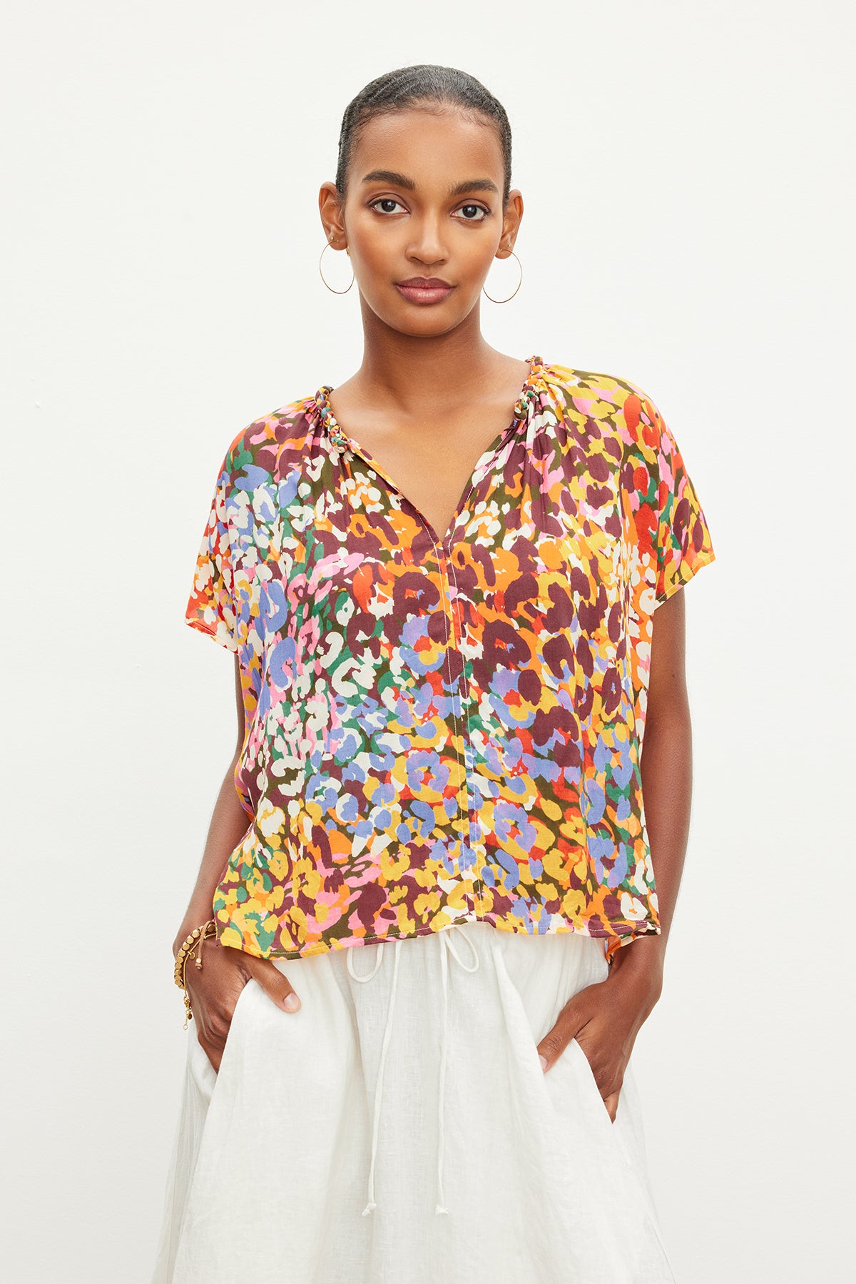 A woman wearing a Velvet by Graham & Spencer TRIXY PRINTED COCOON TOP and white pants.-35967708201153