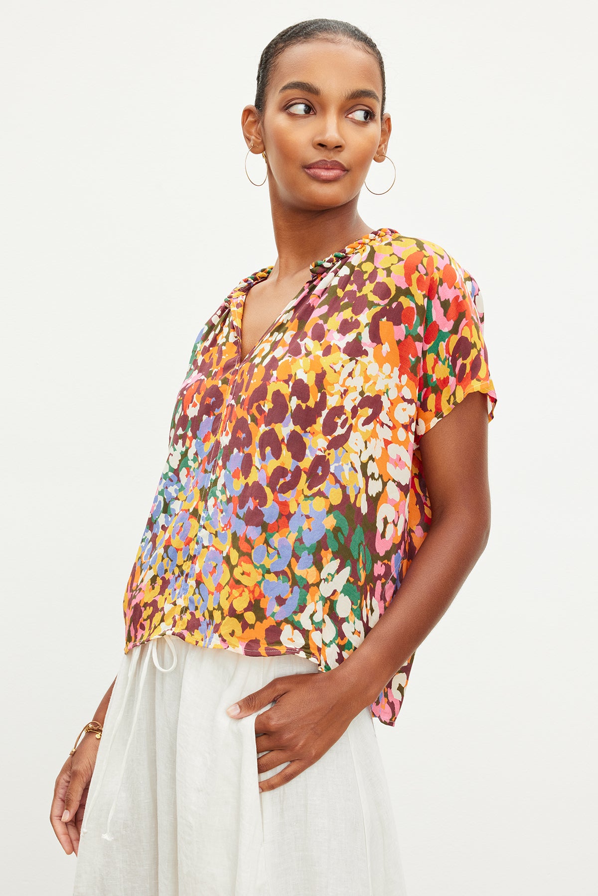 A woman wearing a TRIXY PRINTED COCOON TOP by Velvet by Graham & Spencer and white pants.-35967708266689