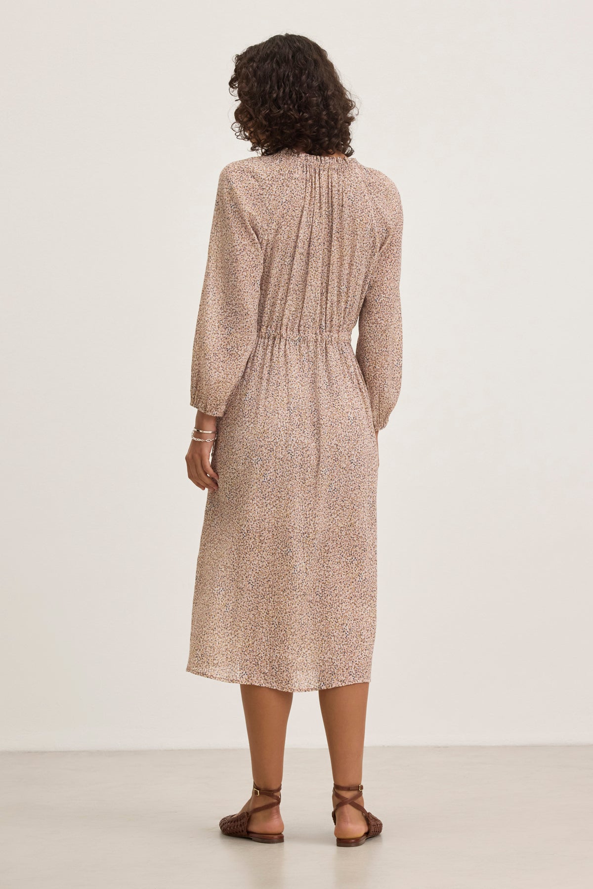 A person with curly hair is wearing the Velvet by Graham & Spencer LIMA PRINTED CRINKLE COTTON GAUZE DRESS and brown sandals, standing facing away against a plain background.-38820676337857