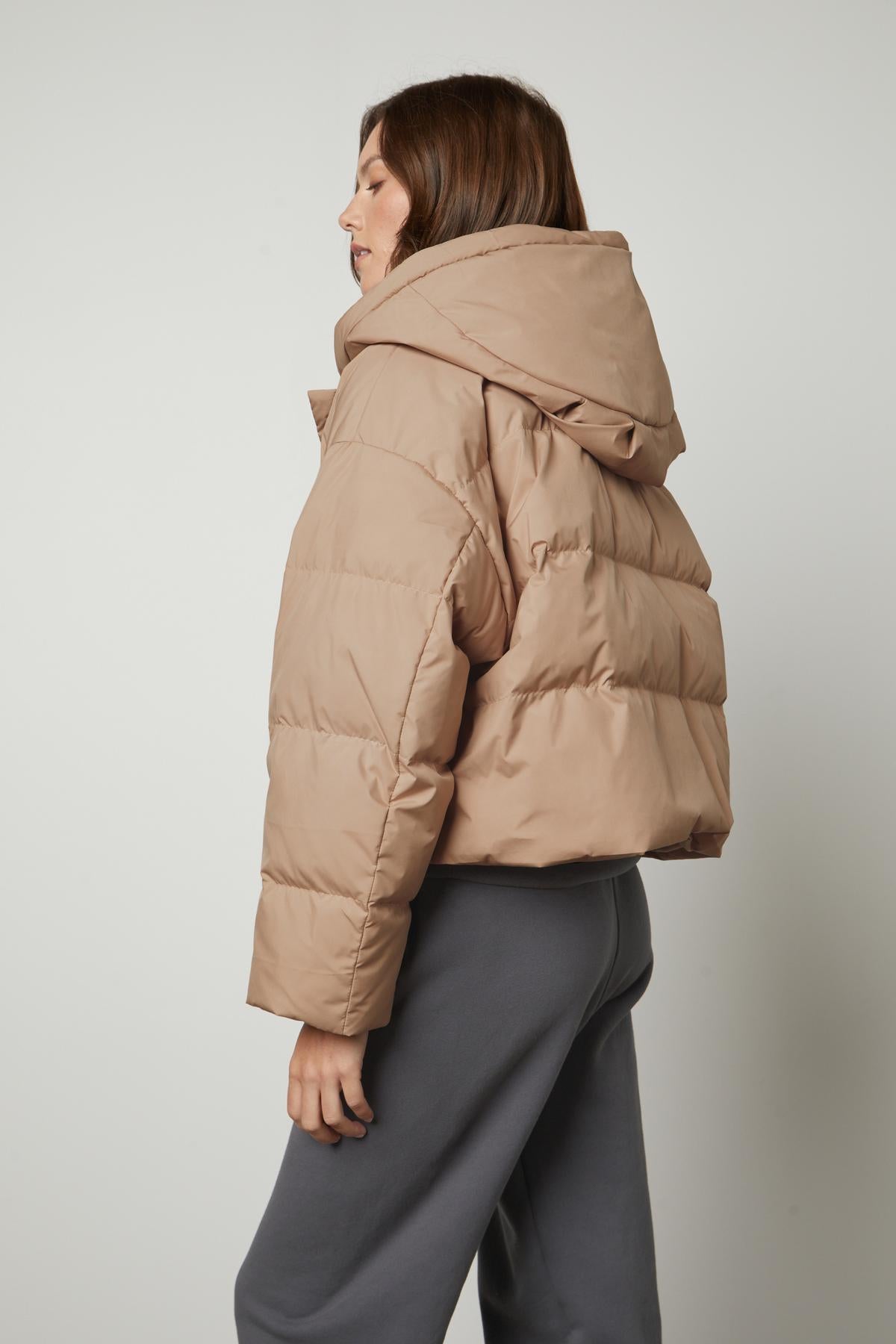The back view of a woman wearing a Velvet by Graham & Spencer RAYLIN CROPPED PUFFER JACKET.-26910089773249